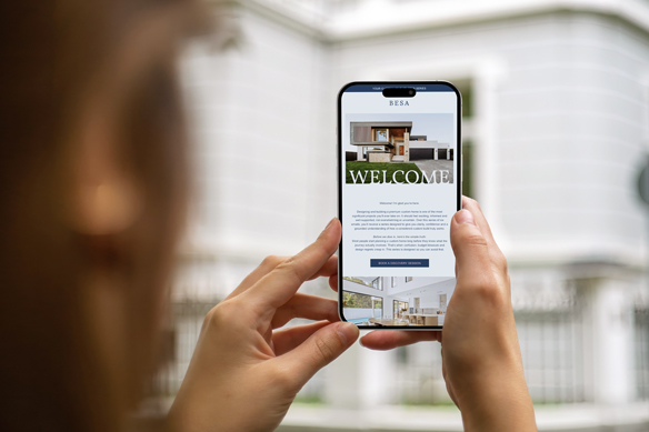 A person holding a phone reading the BESA custom home email series